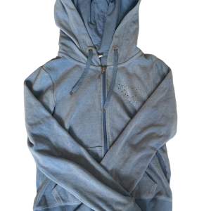 en söt zip up hoodie från cubus, blivit använd 2 ggr! har rhinestones format som ett hjärta på framsidan! den är ljusblå, fråga om mer bilder!