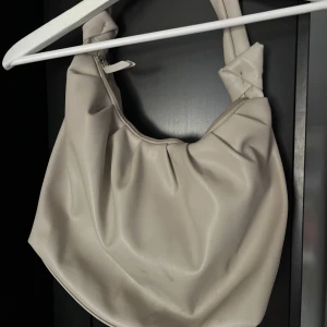 Beige / vit väska - En beige vit väska. Den har ett svart/brunt märke men det är inget man tänker på. Tror det går att få väck men har inte försökt.