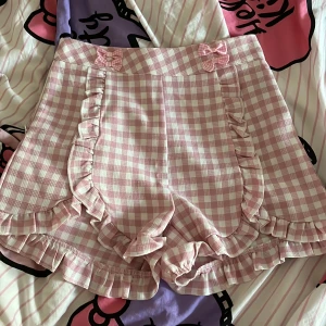 Rosa rutiga shorts med rosetter - Säljer för att jag bara har anvlnt en gång. Bra material med fina rosetter på. Perfekta för sommaren. Är du intresserad/vill ha fler bilder/har frågor så kontakta mig. 