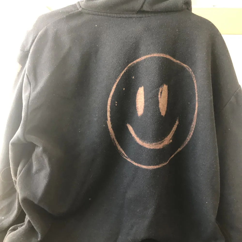 En svart zip-up hoodie med ett tryck av blekningsmedel. Hoodies.