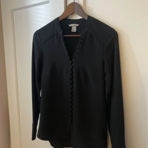 Blus med särskilt fin knäppning - Så fin blus med klädda knappar och snygg ringning. Bara använd någon enstaka gång, blev lite lite för liten för mig. Normal i storlek (jag chansade fel)