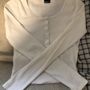 Vit långärmad topp - En vit långärmad topp från Gina Tricot i storlek S.😍 Jag har klippt den lite kortare där nere så den ska sitta som en magtröja. Köparen står för frakten. Använt den ett fåtal gånger. Den har ett litet hål på armen som knappt syns😙🫶