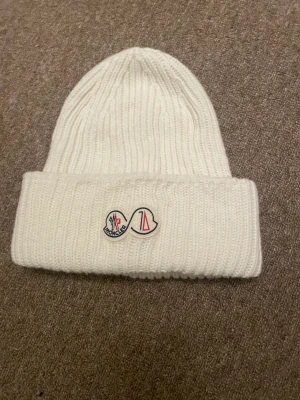 Moncler Mössa - Säljer denna moncler mössa ifrån monclers sjuttio års jubileum i färgen vit riktigt stil ren