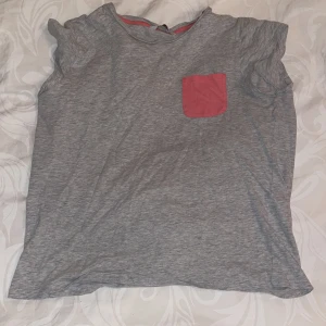 Pj tröja - En grå pyjamas tröja med en rosa ficka på 