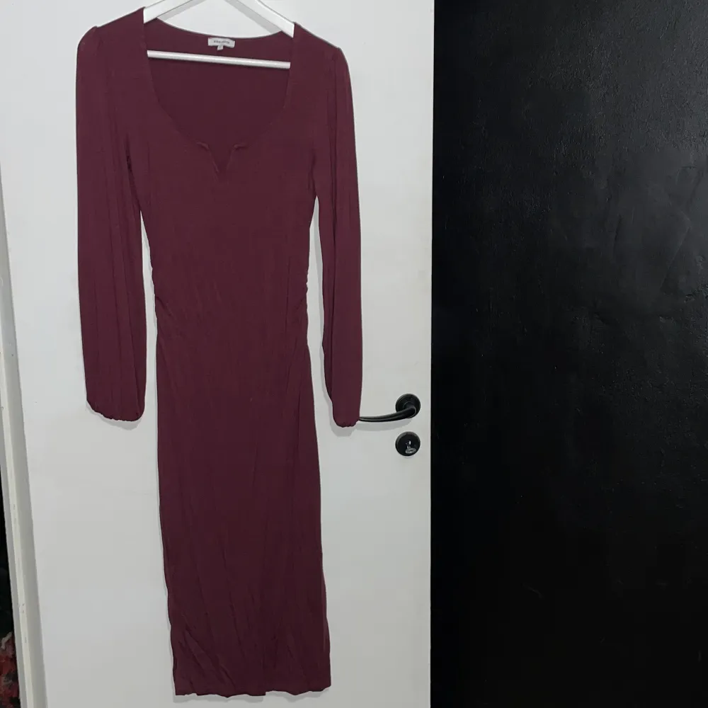 Detta är en relativt lång klänning (som kommer mig som är 173cm lång precis över knäna), i en fin vinröd färg, som sitter tajt på kroppen. . Klänningar.