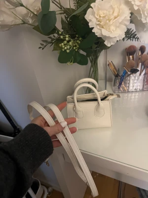 Liten vit väska - Säljer denna lilla vita väskan, perfekt för kort, bilnycklar och läppglans… 💋använd 1-3 gånger, kommer med axelremsband!