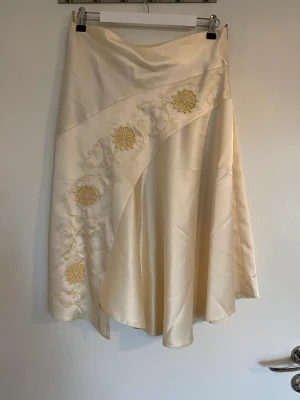 Fin medelång satinkjol - Lågmidjade mid-satinkjol med blommor och coola tyger