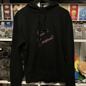 Saint Laurent rosa glitter hoodie - Sitter lite mindre i storlek. Lappen säger Medium men jag skulle säga att den är en small. Skicket är väldigt bra utan skador.