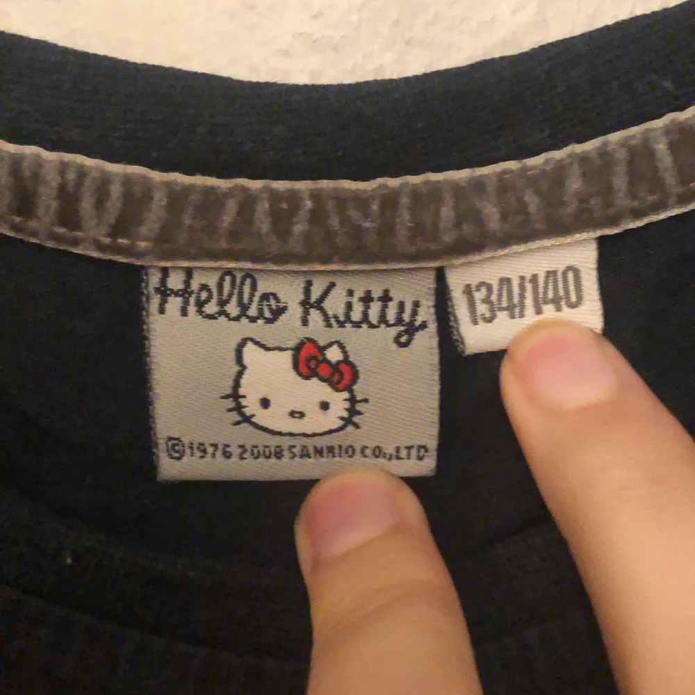 En svart t-shirt med Hello Kitty på ifrån Kappahl💕 Inga defekter vad jag kan se. Jag som är en liten S kan få på mig den, men den är tajt i armhålorna!. T-shirts.