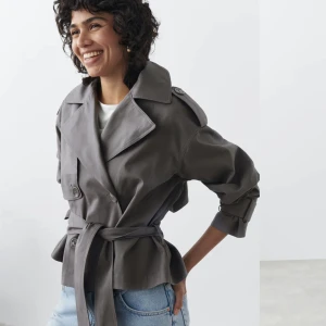 Slutsåld trenchcoat gina - Slutsåld grå trenchcoat från Gina! Aldrig använd, säljer då det gått för lång tid för att lämna tillbaka. Storlek L, frakt tillkommer