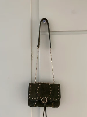 Väska grön mocca  - Väska i grön trendig mocca med axelband som går att bära långt eller kort. Praktiska fickor på insidan. Ca 20x15cm