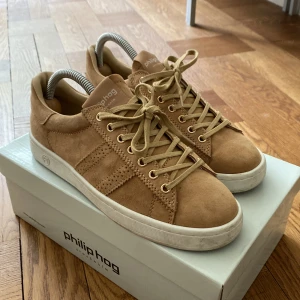 Philip Hog st 37-38 - Fina beiga sneakers i mocka. Använda ett fåtal gånger. Storlek 37. Men ganska stora så 37,5 funkar också!  Fodrade med kalvskinn. Kvalitetsskor! 