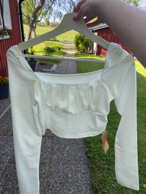 Topp -  en vit långärmad topp,den är lite för liten och kostar 45kr+ 35kr frakt.Viktigt ska jag tvätta den innan köp eller ska jag tvätta den efter köp, viktig måste tvättas.Är helt ny har inte andvänd.