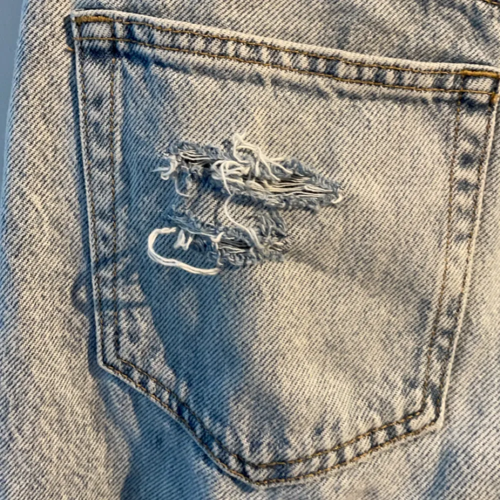 Blåa jeans som är lågmidjade, detaljer på fickan bak och nere vid benen, 1 hål i knäet. Jeans & Byxor.