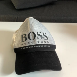 Hugo Boss Keps - En grå Hugo Boss keps utmärkt till vår och sommaren. Den är i okej skick. 
