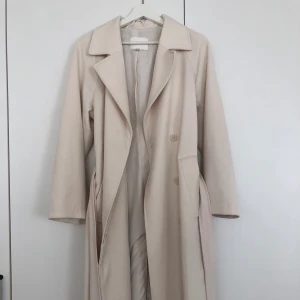 Trenchcoat H&M - Krämvit/ljusbeige trenchcoat från H&M, knappt använd. Säljs då den är för liten för mig Storlek XS, passar även S  Färgen syns bäst på sista bilden🤍