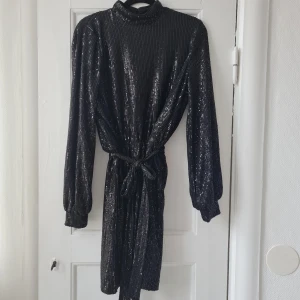 Paljettklänning - Paljettklänning med liten krage och matchande band i midjan. Använd endast 1 gång. Nypris 599 kr
