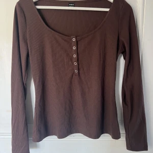 Ribbad Långärmad  - En brun långärmad med urringning och knappar. Strl M. Aldrig använd. 40 kr. Betalning sker endast via swish och köparen betalar frakten 🤎