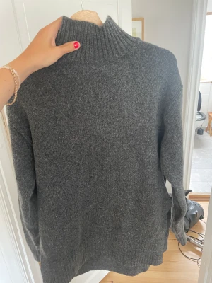 Stickad tröja  - En mörkgrå stickad tröja ifrån H&M den har hög krage och slits nertill. Använd 2gånger. Storlek XS men mer som en S ganska lång i modellen.