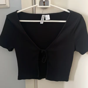 Kortärmad svart kofta  - En kortärmad svart kofta från hm, säljer då den inte kommit till användning en ända gång. S men passar mig som xs med