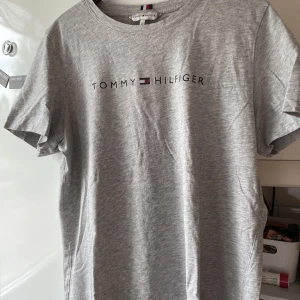 Tommy Hilfiger T-shirt - Säljer min t-shirt från Tommy Hilfiger! Använd väl men fortfarande i väldigt bra skick. Ett pyttelitet hål finns längst ner på tröjan (se bild 3), men det märks inte när man har den på sig💛 Storlek M men skulle säga att den passar S bättre☺️💛