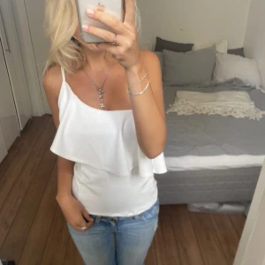 Vit topp - Säljer denna ”one shoulder” linne med volang. Direktpris: 200kr. Har du någon fråga är det bara att höra av dig🫶🏻