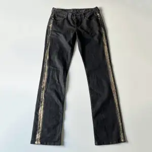 Svarta lågmidjade jeans från IKKS med guldfärg på sidorna. Midjemått: 76 cm, stretchiga. Innerbenslängd: 86 cm. Jag är 176 cm