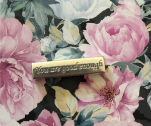 Hänge Gynning  - Ca 2cm i silver. En sidan har texten ”Your good enough” och sen andra en liten fjäril. Ingen kedja med. 