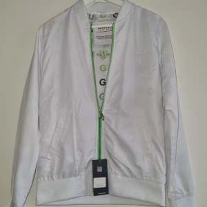 Hugo boss jacka - Vit tunnare jacka med gröna detaljer som lyser igenom något. Oanvänd.