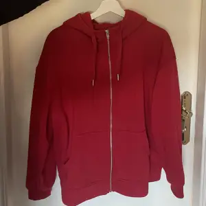 En röd hoodie med dragkedja Storlek XL men skulle säga att den är mindre. Den passar som oversized på mig som brukar ha ungefär XS❤️ Endast använd ett fåtal gånger och i mycket bra skick! Original pris: 400kr. Tryck gärna på köp nu!😊