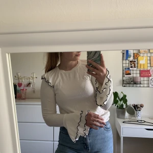 Topp - Vit topp med volanger och svarta detaljer från Mango. Skön och tunn i materialet. Pris kan diskuteras!