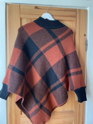 Poncho  - Rutig poncho med handleder.  