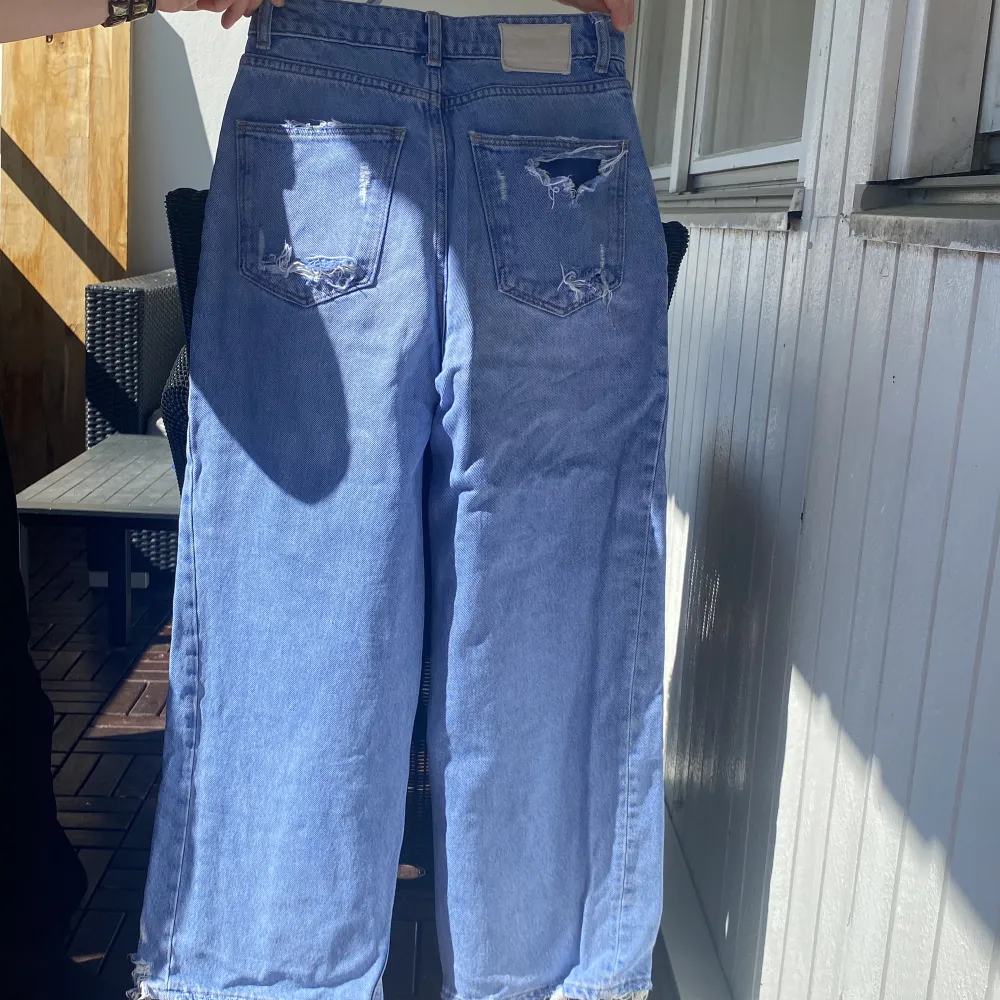 Ett par blåa baggy jeans som är perfekta inför sommaren. Några små hål på byxorna och slitet längst ner  ( modellen är så ) . Jeans & Byxor.