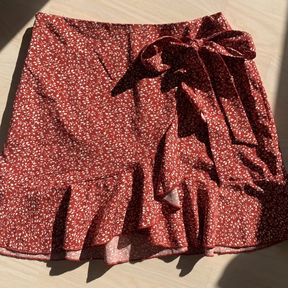 Jättefin röd kjol med vita detaljer på ❤️ endast testad, säljer pga att den aldrig kommer till användning. Väldigt härligt tyg med blixtlås i sidan och knytning, perfekt nu till sommaren 🫶🏻☀️. Kjolar.