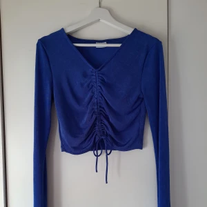 Långärmad blå topp från Noisy May - Långärmad blå topp från Noisy May i storlek M! I toppenfint skick, aldrig använd. Stretchigt, smickrande tyg och skön att ha på sig. Snörning som kan justera längen. Funkar lika bra att ha med knytningen fram eller bak, som två toppar i en! 💙