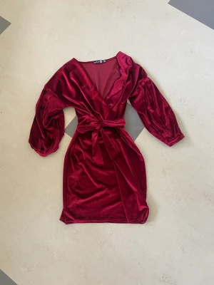 Vinröd fin-klänning i sammet - Aldrig använd, Ny skick! Den har ett band i midjan där man kan spänna in hur mycket/lite man vill! Passar jätte bra till fester/finmiddagar!