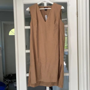 Klänning - Ny klänning från Lindex, snygg med ett par vida byxor under. Brunbeige färg