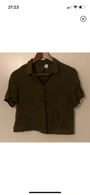 Croppad skjorta - En mörkgrön kort löst sittande skjorta med kort ärm, aldrig använd (lite skrynklig men skicket är som ny) Minns inte var jag köpt den🌱 passar mig som vanligen har storlek S-M