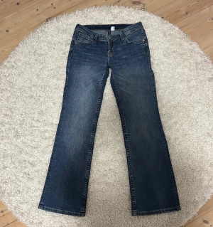 Lågmidjade jeans  - Blå lågmidjade jeans från H&M med mönster på fickorna. Storlek 40. Stretchigt tyg. 