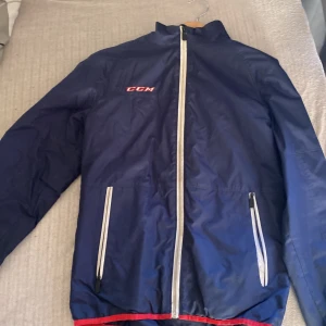 CCM överdrags jacka - Blå CCM hockey jacka. Detta är ens familj medlem som spelade hockey i 3 år. Använd men i bra skick för utom lite smuts. I strl XS för killar. Köpt nytt från intersport
