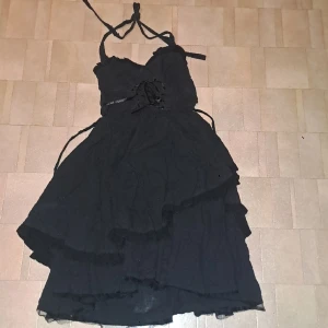 Svart klänning  - Svart klänning med många tyglager med snörning på framsidan under bysten. Sutter vid knäna på mig som är 167