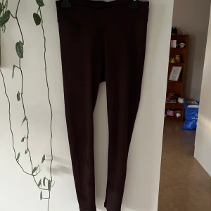 Bruna Ribbade träningstights - Bruna Ribbade träningstights från hm med v-skurning framtill. Skönt material använd ett fåtal gånger men aldrig att träna i, passar inte mig som har S utan då hasar dem ner så rekommenderar att bara köpa om du har M