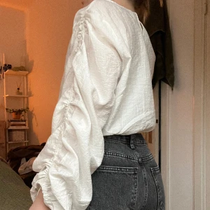 Blus med fin detalj  - Vit blus med fin snörningsdetalj på ärmarna. Resår i midjan. Aldrig använd! 