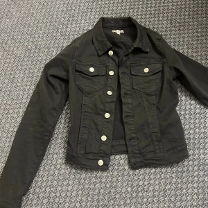  jeansjacka - Svart jeansjacka som är kort i modellen och har långa ärmar! Endast använd ca 3 gånger o säljs pga att den inte passar min stil längre 