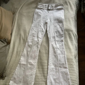 Byxor med bälte - Säljer dessa vita mid rise byxor med bälte detalj. Aldrig använt och är i bra sick. Är storlek M men passar fint på även S. 