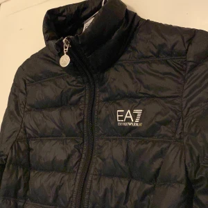 Svart EA7 jacka - En EA7 jacka som är i bra skick och är använd ett få antal gånger. Är inte säker på storleken men tror att den passar xs och s eftersom den är för liten för mig. Kontakta om ni undrar något😊