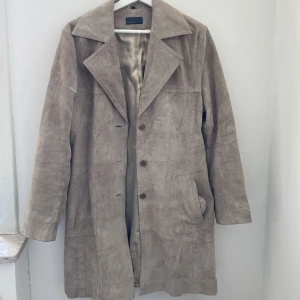 Snygg vårjacka  - Skitsnygg vårjacka i något mocka aktigt material (hittar ej någon material lapp) två innerfickor och tillhörande midjeband finns. Endast använd en gång av mig men köpt secondhand. Ett litet hål i ena fickan som enkelt går att sy igen. 