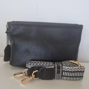 Väska - Svart väska i skinn, oanvänd. Mönstrat axelband.