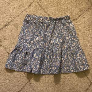 En blå blommig kjol köpt från Shein för 60kr säljer för 40kr. Storlek 12-13, midjemått: 73, längd: 38