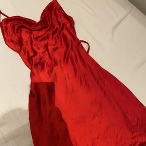 Röd klänning - Skit snygg röd klänning. I satin med ett band bak för att framhäva midjan. Säljer den pga att den inte passar mig längre. Använd en gång på jul, i storlek S men passar även XS/M för den går att justera. Ordinarie pris 500kr.